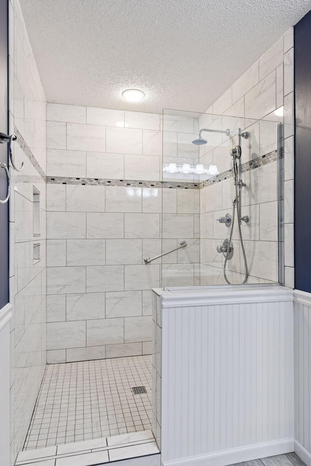 1040 Primrose Ln, Waconia, MN 55387 - bathroom featuring a textured ceiling, a tile shower, and wainscoting
