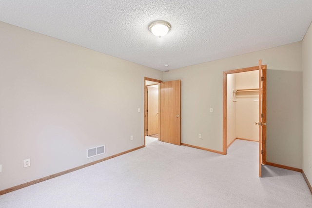 1040 Primrose Ln, Waconia, MN 55387 - unfurnished bedroom featuring a walk in closet, carpet, a closet, and a textured ceiling