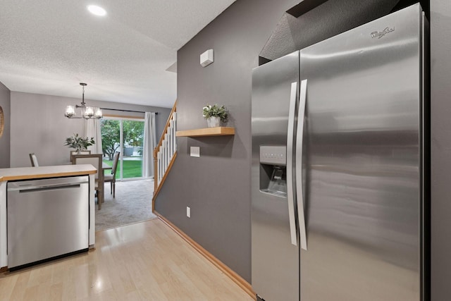 5425 Fawn Ct SE, Prior Lake, MN 55372 - kitchen featuring stainless steel appliances, light wood-type flooring, a chandelier, a textured ceiling, and decorative light fixtures