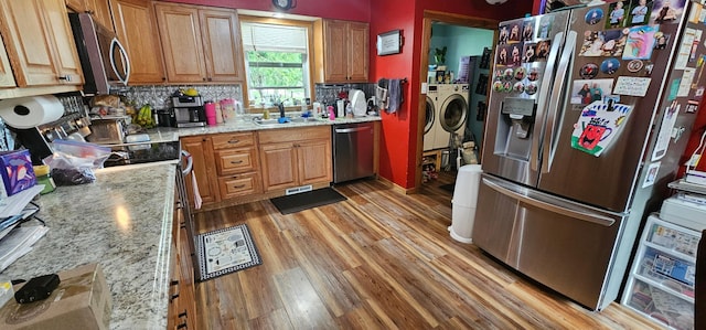 210 E St S, Underwood, MN 56586 - kitchen featuring appliances with stainless steel finishes, washer and dryer, a sink, light wood-style floors, and decorative backsplash