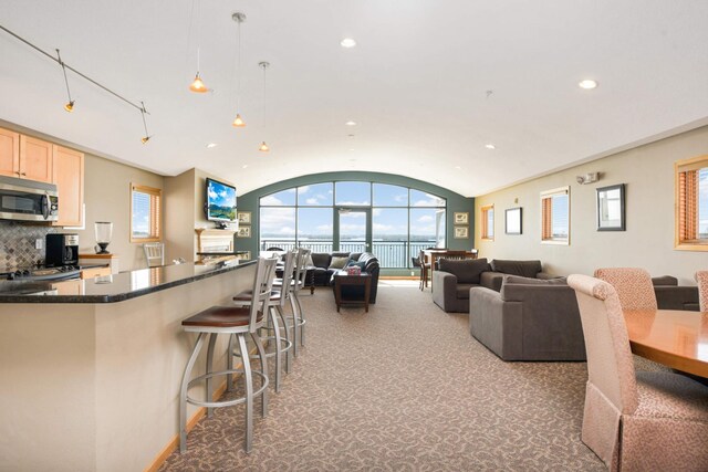 4100 Spring St Unit 310, Spring Park, MN 55384 - kitchen featuring stainless steel microwave, open floor plan, recessed lighting, a breakfast bar area, and light brown cabinetry