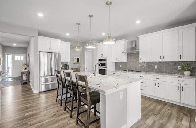 5201 Ramier Ave NE, Otsego, MN 55374 - kitchen with stainless steel appliances, wall chimney exhaust hood, dark wood finished floors, backsplash, and a kitchen breakfast bar