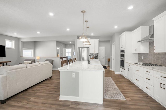 5201 Ramier Ave NE, Otsego, MN 55374 - kitchen featuring appliances with stainless steel finishes, wall chimney range hood, backsplash, open floor plan, and white cabinetry