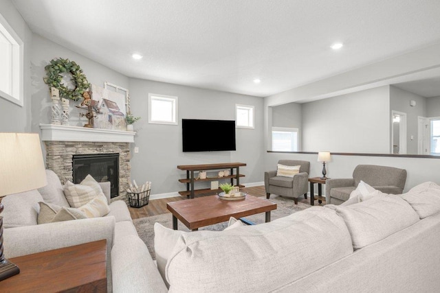 5201 Ramier Ave NE, Otsego, MN 55374 - living room featuring wood finished floors, a stone fireplace, plenty of natural light, recessed lighting, and baseboards