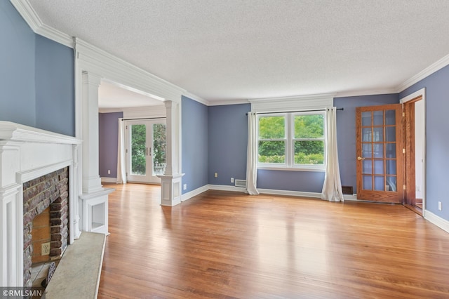 76 Western Ave N, Saint Paul, MN 55102 - unfurnished living room with a textured ceiling, ornate columns, wood finished floors, a fireplace, and crown molding