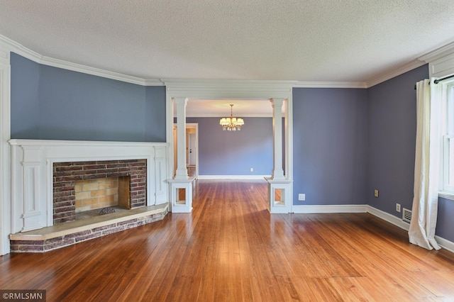 76 Western Ave N, Saint Paul, MN 55102 - unfurnished living room with ornate columns, wood finished floors, a chandelier, a textured ceiling, and crown molding