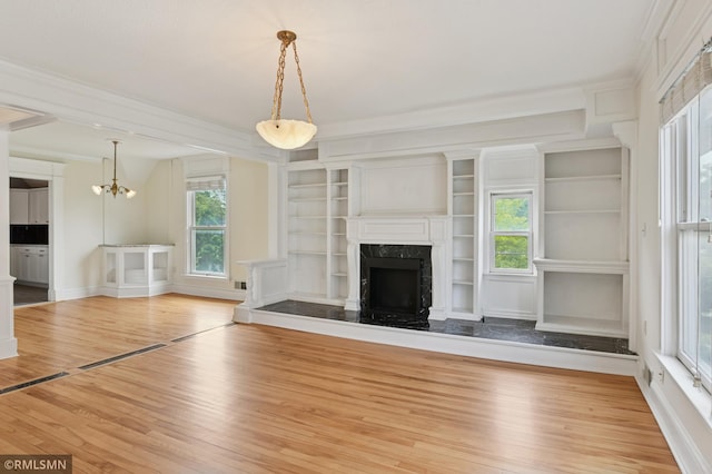 76 Western Ave N, Saint Paul, MN 55102 - unfurnished living room featuring wood finished floors, a fireplace, a chandelier, crown molding, and built in features