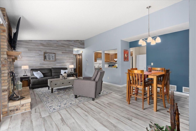 7079 Robinwood Trl, Woodbury, MN 55125 - living room with an accent wall, a chandelier, light wood-style flooring, vaulted ceiling, and wooden walls