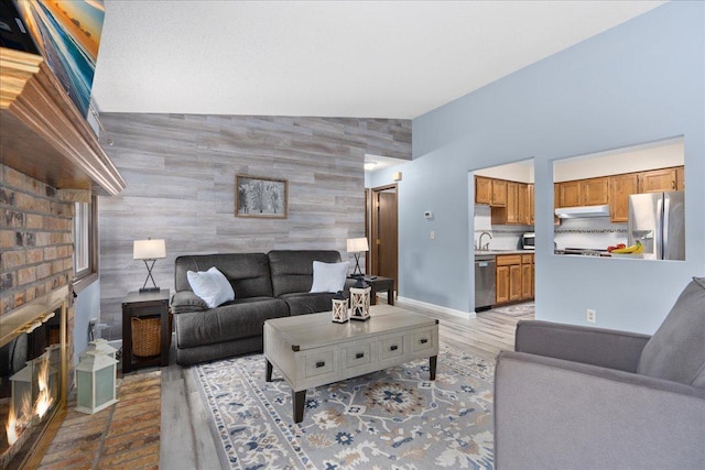 7079 Robinwood Trl, Woodbury, MN 55125 - living room featuring an accent wall, a brick fireplace, and light wood-style floors