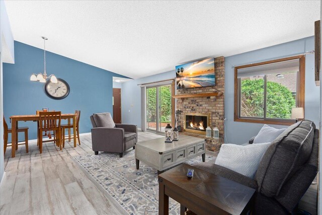7079 Robinwood Trl, Woodbury, MN 55125 - living area with a chandelier, lofted ceiling, light wood finished floors, a brick fireplace, and a textured ceiling