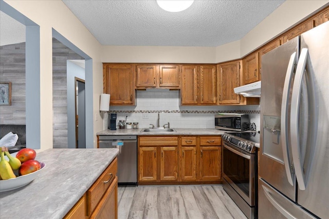 7079 Robinwood Trl, Woodbury, MN 55125 - kitchen with stainless steel appliances, under cabinet range hood, brown cabinets, and a textured ceiling