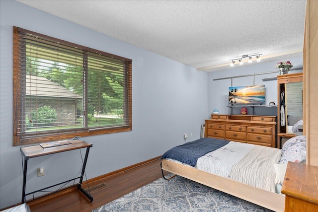 7079 Robinwood Trl, Woodbury, MN 55125 - bedroom featuring wood finished floors, a textured ceiling, and a baseboard heating unit