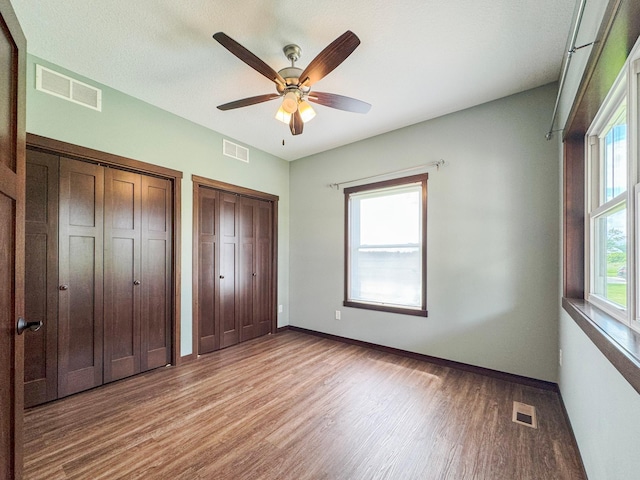 39847 447th St, Sauk Centre Twp, MN 56378 - unfurnished bedroom with multiple closets, wood finished floors, baseboards, and ceiling fan