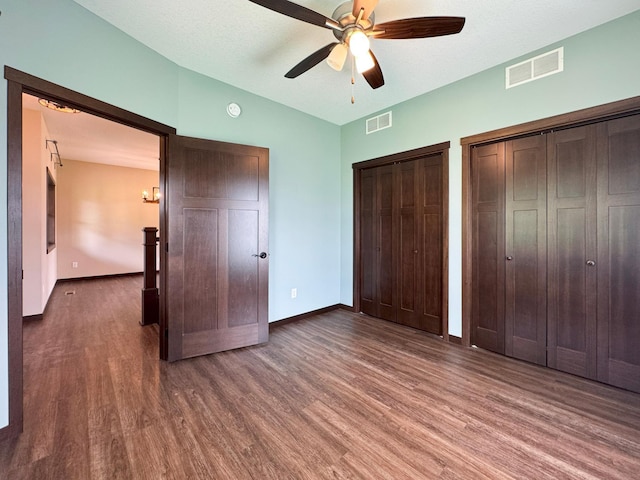 39847 447th St, Sauk Centre Twp, MN 56378 - unfurnished bedroom with two closets, wood finished floors, baseboards, lofted ceiling, and ceiling fan