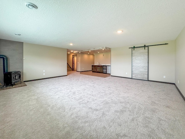 39847 447th St, Sauk Centre Twp, MN 56378 - unfurnished living room featuring a textured ceiling, a wood stove, carpet floors, stairs, and baseboards