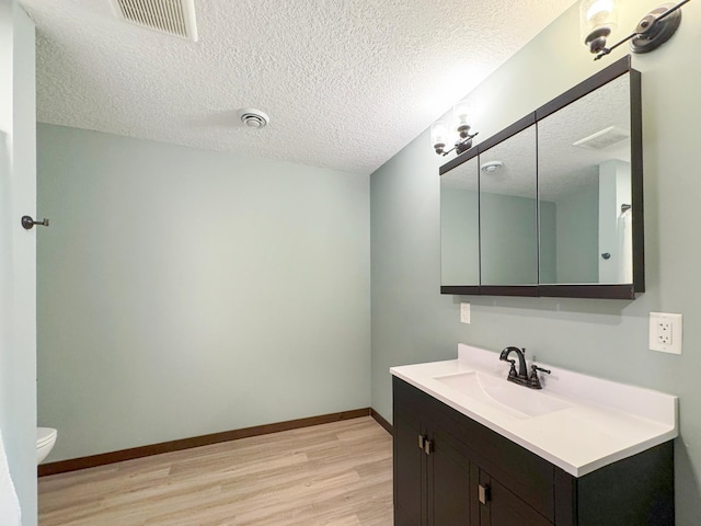 39847 447th St, Sauk Centre Twp, MN 56378 - bathroom with wood finished floors, vanity, toilet, a textured ceiling, and baseboards