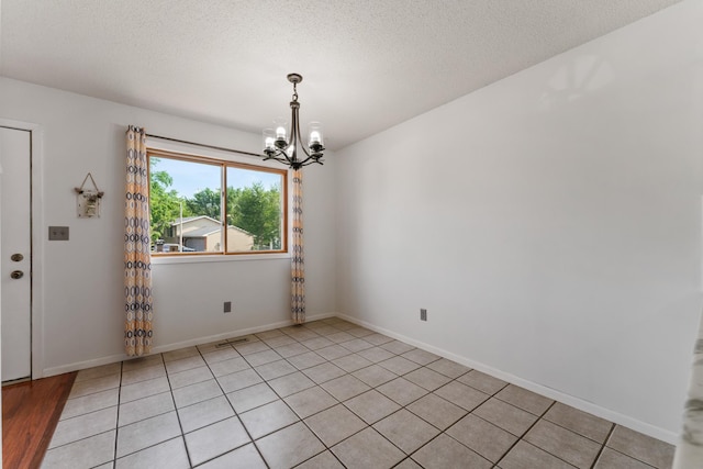 2452 Parkview Ln SE, Rochester, MN 55904 - empty room featuring a chandelier, a textured ceiling, baseboards, and light tile patterned floors
