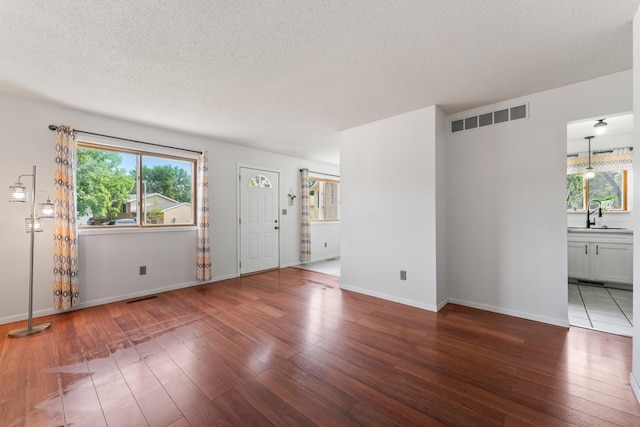 2452 Parkview Ln SE, Rochester, MN 55904 - unfurnished living room with hardwood / wood-style flooring, a textured ceiling, a sink, and baseboards