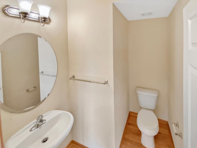 15579 June Grass Ln, Eden Prairie, MN 55347 - half bath featuring toilet, a sink, wood finished floors, and baseboards