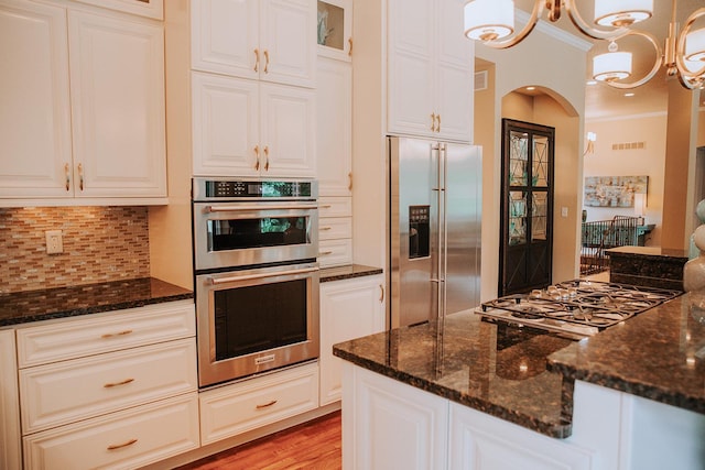 1509 Haller Ct S, Maplewood, MN 55119 - kitchen featuring appliances with stainless steel finishes, dark stone countertops, crown molding, backsplash, and a chandelier