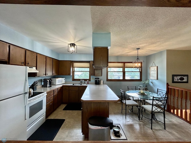 1922 13th Ave N, Moorhead, MN 56560 - kitchen featuring white appliances, under cabinet range hood, a peninsula, light countertops, and decorative light fixtures
