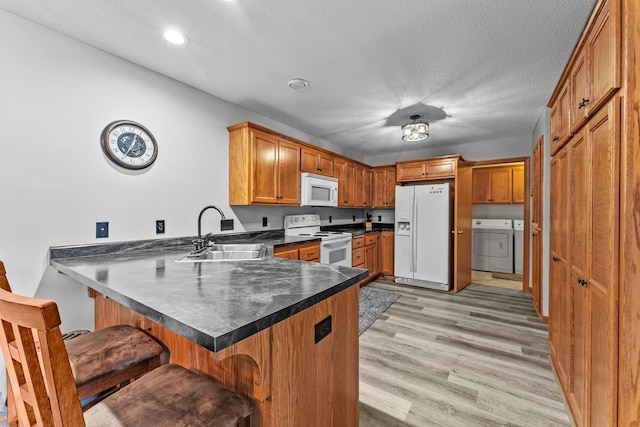 315 Roosevelt St S Unit B, Cambridge, MN 55008 - kitchen with white appliances, a sink, washer and clothes dryer, a peninsula, and a kitchen bar