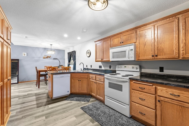 315 Roosevelt St S Unit B, Cambridge, MN 55008 - kitchen featuring white appliances, a sink, a peninsula, light wood finished floors, and dark countertops