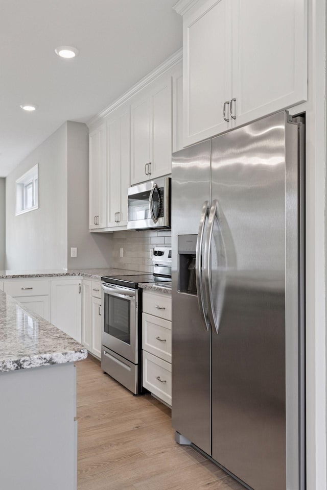 1250 Naser Way, New Richmond, WI 54017 - kitchen with appliances with stainless steel finishes, white cabinetry, light wood-style flooring, backsplash, and a peninsula