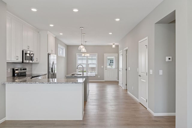 1250 Naser Way, New Richmond, WI 54017 - kitchen with appliances with stainless steel finishes, light wood finished floors, light stone countertops, white cabinetry, and recessed lighting