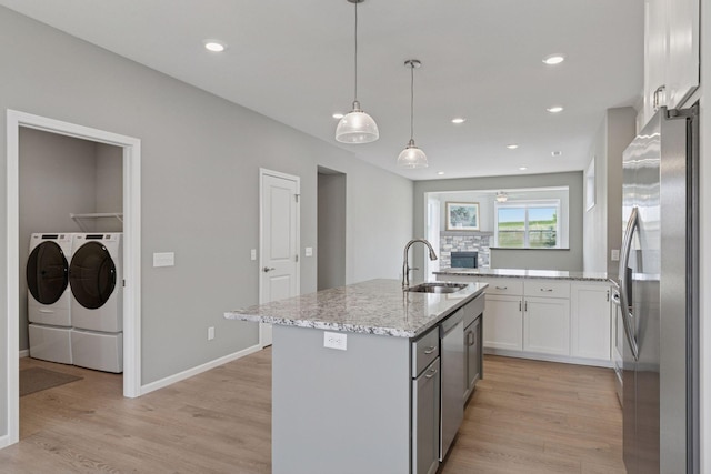 1250 Naser Way, New Richmond, WI 54017 - kitchen with appliances with stainless steel finishes, washing machine and dryer, light wood-style flooring, light stone countertops, and white cabinets