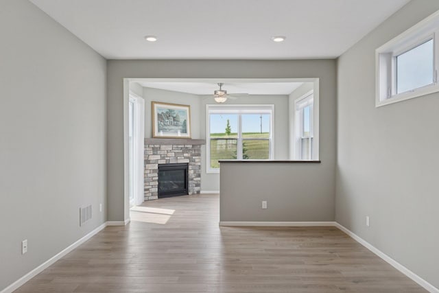 1250 Naser Way, New Richmond, WI 54017 - unfurnished living room with ceiling fan, wood finished floors, a stone fireplace, and recessed lighting