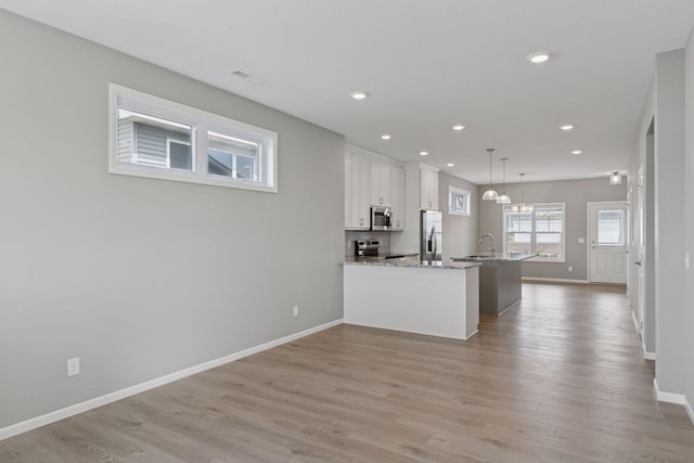 1250 Naser Way, New Richmond, WI 54017 - kitchen with appliances with stainless steel finishes, white cabinetry, light wood-style flooring, recessed lighting, and decorative light fixtures