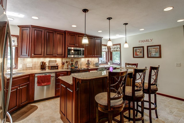 305 Birch Briar Ln, Park Rapids, MN 56470 - kitchen with stainless steel appliances, decorative backsplash, a center island, a kitchen bar, and hanging light fixtures