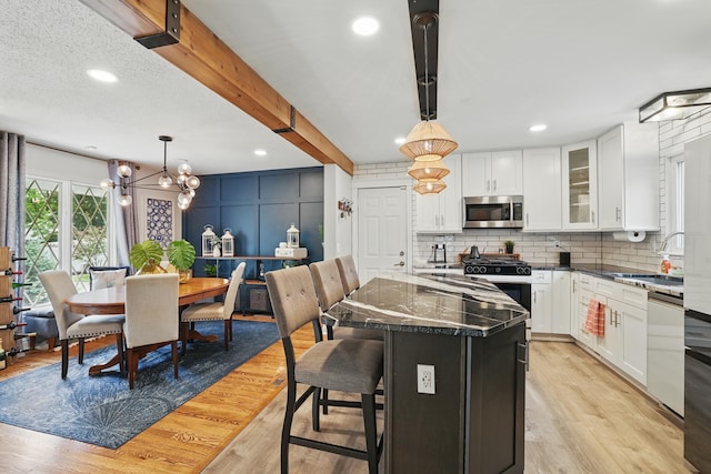3940 Virginia Ave N, New Hope, MN 55427 - kitchen featuring stainless steel microwave, range with gas stovetop, decorative backsplash, white cabinets, and dishwashing machine