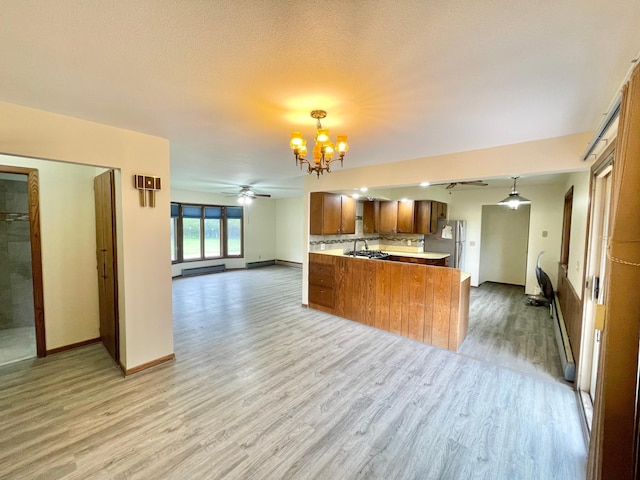 605 13th St, Mountain Lake, MN 56159 - kitchen with freestanding refrigerator, brown cabinetry, a sink, a chandelier, and open floor plan