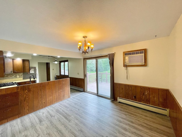 605 13th St, Mountain Lake, MN 56159 - kitchen featuring baseboard heating, light wood finished floors, a wainscoted wall, a chandelier, and a wall mounted AC