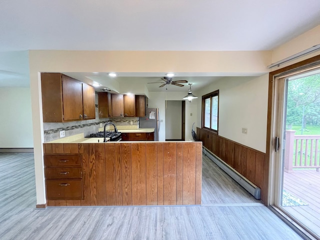 605 13th St, Mountain Lake, MN 56159 - kitchen with baseboard heating, light wood-style floors, freestanding refrigerator, light countertops, and wainscoting