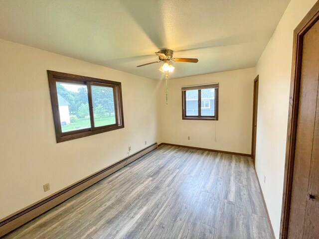 605 13th St, Mountain Lake, MN 56159 - unfurnished room with a baseboard radiator, light wood-style floors, a ceiling fan, and baseboards