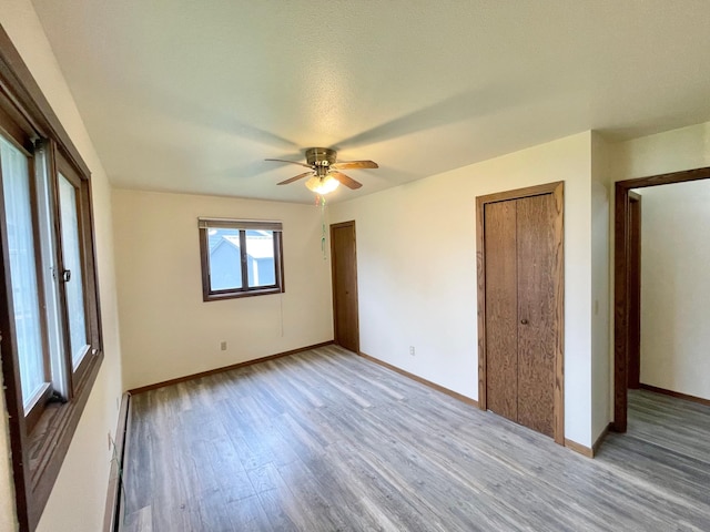 605 13th St, Mountain Lake, MN 56159 - unfurnished bedroom with wood finished floors, baseboards, a baseboard radiator, and a ceiling fan