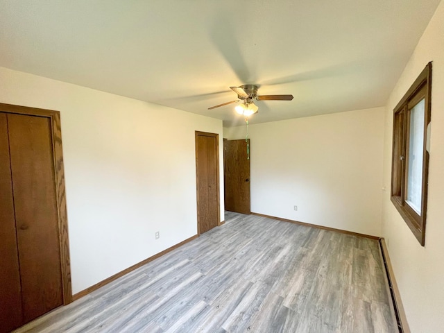 605 13th St, Mountain Lake, MN 56159 - unfurnished bedroom with wood finished floors, baseboards, a ceiling fan, and a baseboard radiator