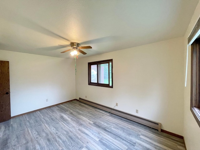 605 13th St, Mountain Lake, MN 56159 - unfurnished room featuring a baseboard radiator, wood finished floors, a ceiling fan, and baseboards