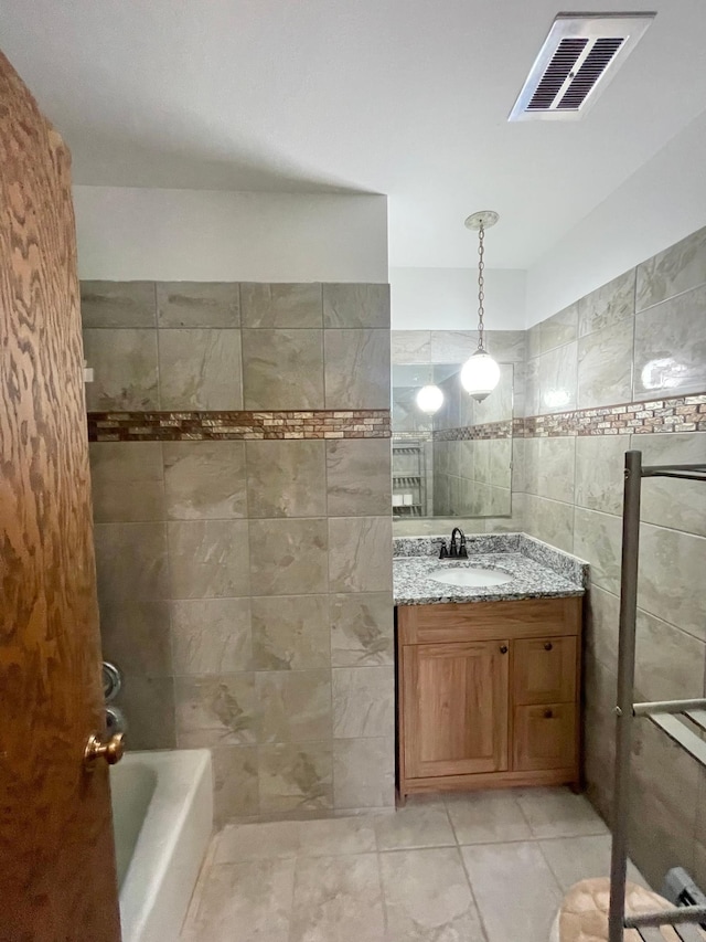 605 13th St, Mountain Lake, MN 56159 - bathroom with tile walls, vanity, tile patterned flooring, and washtub / shower combination