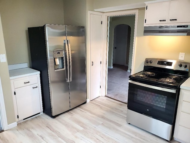 2512 7th Ave E, Hibbing, MN 55746 - kitchen with appliances with stainless steel finishes, ventilation hood, light wood finished floors, arched walkways, and white cabinets