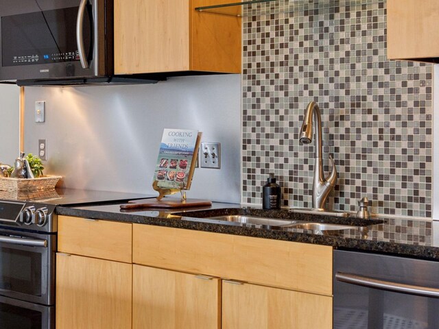 730 Stinson Blvd Unit 106, Minneapolis, MN 55413 - kitchen featuring appliances with stainless steel finishes, light brown cabinetry, dark stone countertops, and backsplash