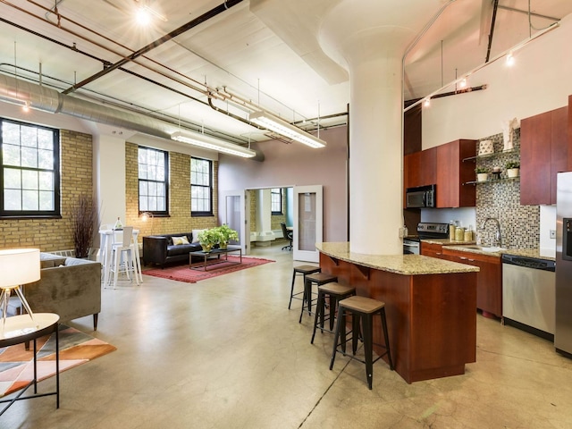 730 Stinson Blvd Unit 106, Minneapolis, MN 55413 - kitchen with appliances with stainless steel finishes, open floor plan, a towering ceiling, a kitchen bar, and open shelves