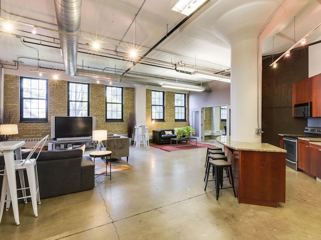 730 Stinson Blvd Unit 106, Minneapolis, MN 55413 - kitchen with stainless steel electric range, brick wall, black microwave, a kitchen bar, and open floor plan