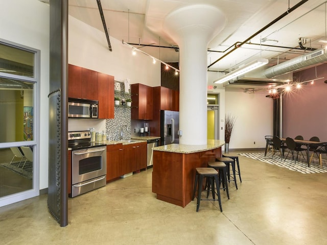 730 Stinson Blvd Unit 106, Minneapolis, MN 55413 - kitchen featuring stainless steel appliances, a kitchen breakfast bar, finished concrete floors, a towering ceiling, and modern cabinets