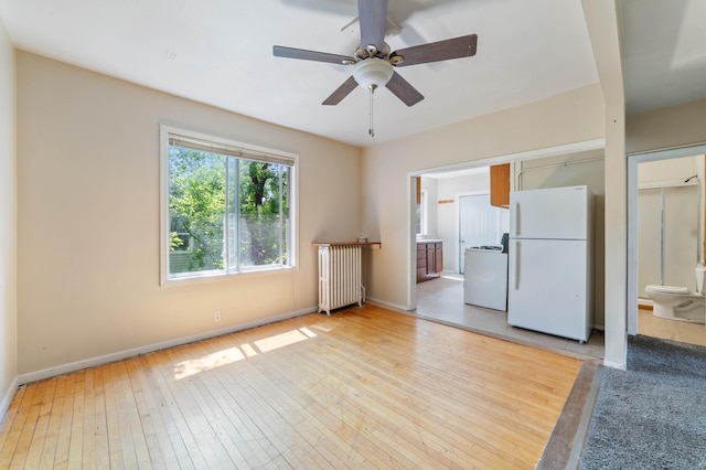 1511 4th St, Duluth, MN 55812 - unfurnished living room featuring radiator, a ceiling fan, baseboards, and light wood-style flooring