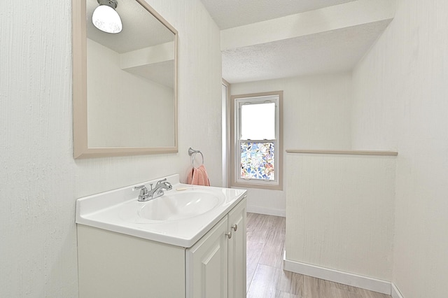 409 3rd St, Bovey, MN 55709 - bathroom with vanity, baseboards, wood finished floors, and a textured ceiling