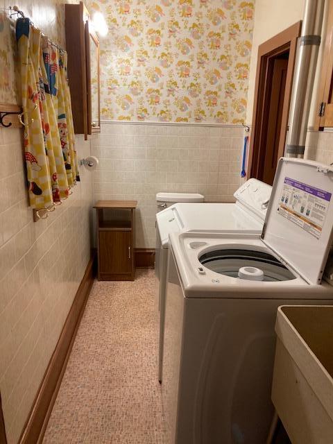 201 Cherry St, Lowry, MN 56349 - laundry room with wallpapered walls, separate washer and dryer, wainscoting, and tile walls